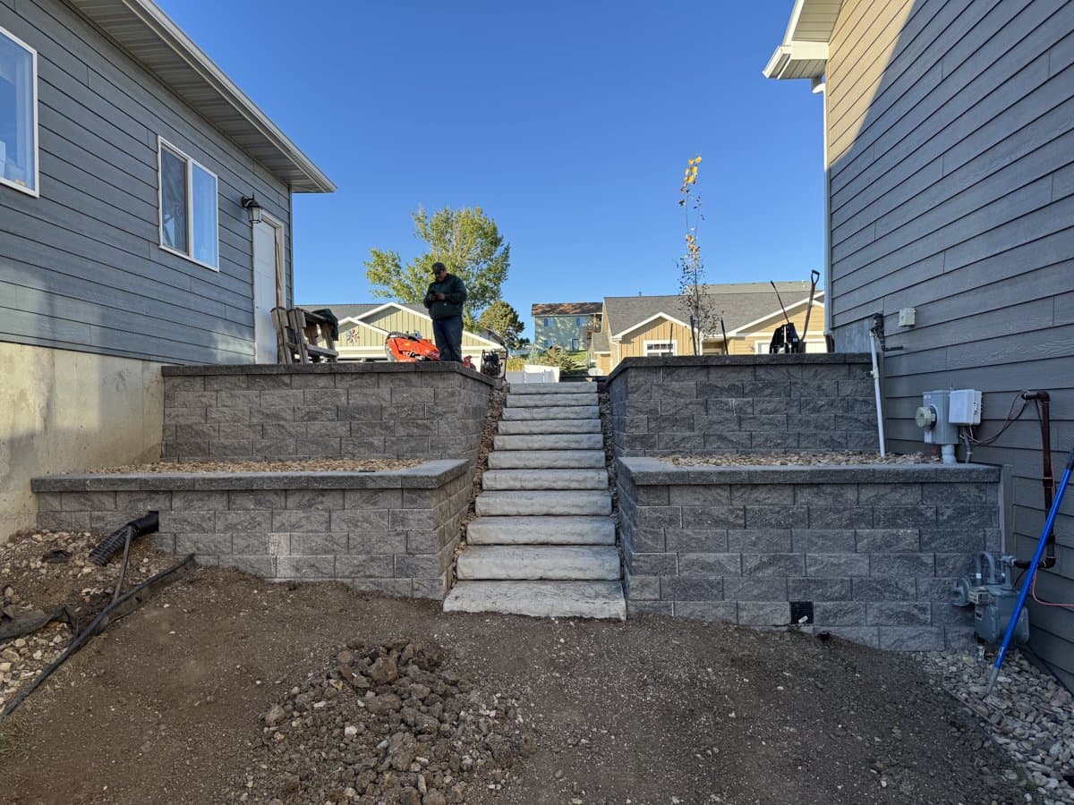 Completed multi-tier retaining wall with stone steps on stabilized hillside